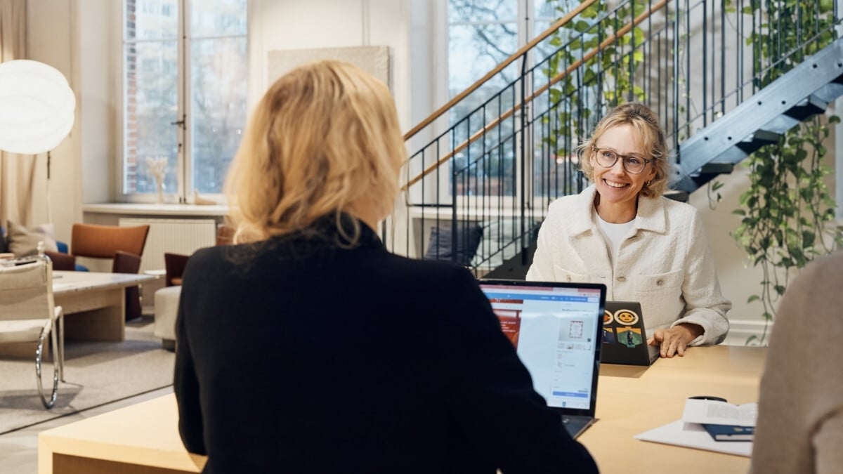 Två kvinnliga kollegor som sitter och pratar samtidigt som de jobbar
